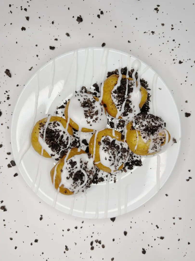 A plate of donuts with cream and crushed chocolate cookies on top